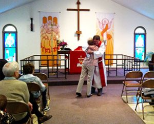 The Rev. Michael Dunne, pastor of St. Thomas Lutheran Church, Manalapan, N.J., hugs Lois Hinds, a member of the congregation, after presenting her with a check during the worship service on Sunday, May 19. (Nancy McGrath)