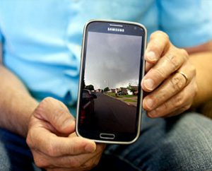 The Rev. Mark Bersche, pastor of St. John's Lutheran Church, Moore, Okla., holds his phone, showing an image he took of the approaching tornado. (Dan Gill)