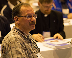 Delegates, including the Rev. Darrell Debowey from the Central Illinois District, listen to Floor Committee 7 propose amendments to Bylaws concerning structure and ecclesiastical matters.