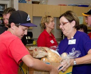 Carol Kriewald, right, a member of Redeemer Lutheran Church in Fort Collins, Colo., accepts a local bakery's donation of bread to the Red Cross shelter in Fort Collins. The shelter provided food, showers, toiletries and other supplies for some 1,200 people who were evacuated from their homes because of flooding. (Redeemer Lutheran Church)