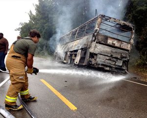 A firefighter aims a hose at the smoldering bus that caught fire as it was carrying football players and coaches from Concordia College Alabama, Selma, to a game at Miles College in Birmingham, Ala. All 62 passengers escaped without injury, but more than $70,000 of equipment was lost. (The Selma Times-Journal/Jay Sowers)