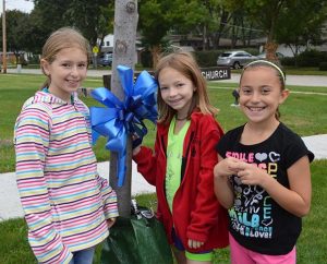 Three third-grade students pose for a photo after tying a blue ribbon to a tree outside St. Peter Lutheran School, Arlington Heights, Ill., during an all-school celebration of St. Peter’s “National Blue Ribbon School” status, which was announced Sept. 24, 2013. (St. Peter Lutheran School)