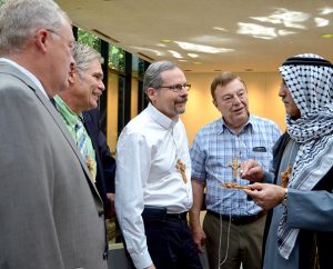 The Rev. Nabil S. Nour, right, the Synod’s new fifth vice-president from Armour, S.D., wears his native Palestinian clothing as he talks with several fellow LCMS Council of Presidents (COP) members about the features of an olive-wood cross centered with a dove that he gave each council member during his opening devotion for the Sept. 20-24 COP meeting in St. Louis. From left, they are Third Vice President Rev. Daniel Preus, Second Vice-President Rev. Dr. John C. Wohlrabe, Northern Illinois District President Rev. Dan P. Gilbert and Indiana District President Rev. Dr. Daniel P. May. (LCMS Communications/Frank Kohn)