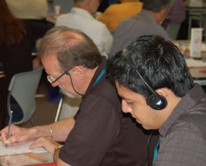 Cristian Morales, a lay leader at Cristo El Salvador Lutheran Church in Del Rio, Texas, listens on headphones to a simultaneous Spanish translation at the Partners in Latino Ministries Conference (PALMCON), Oct. 23-25 in El Paso, Texas. The Rev. Dr. Hector Hoppe, left, served as the conference chaplain. (John Williamson)