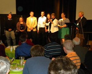 Retiring Lutherans For Life President Diane Schroeder (third from right) introduces her family during the conference banquet. From left are son Paul Schroeder and his girlfriend, Jenell Horvatin; son Michael Schroeder; fiancé Ralph Divenere and daughter  ; Beka Schoeder; daughter Liz Schroeder; and husband Carl Schroeder. Mike’s wife Katie, eight months pregnant, could not attend because of doctor’s orders. (LCMS Communications/Paula Schlueter Ross)