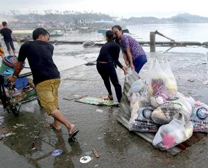 Survivors use a steel roof to carry groceries and supplies in Tacloban city, Leyte province, central Philippines on Sunday, Nov. 10. The city remains littered with debris from damaged homes as many complain of shortages of food and water and no electricity since Typhoon Haiyan slammed into their province. (AP Photo/Aaron Favila)