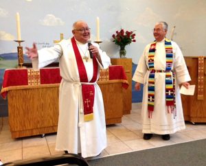 The Rev. Dr. Carlos Hernandez, director of LCMS Church and Community Engagement, left, addresses those gathered for the charter signing of Iglesia Evangelica Luterana Esperanza Viva, a Hispanic congregation in Orlando, Fla. The Rev. Roberto Rojas, right, is the congregation’s pastor. (Esperanza Viva/Awilda Del Valle)