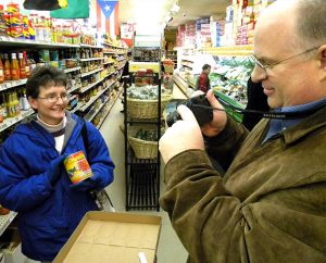 "All right. We're ready to go," the Rev. Dale Kaster tells his wife, Suzanne — snapping a photo of her as she holds up a can of GhanaFresh palm nut oil during the missionary-orientation group's Feb. 10 stop at Jay International Food Co. in South St. Louis. The Kasters, of Jacksonville, Fla., are preparing for life in Ghana, where he will serve as a theological educator preparing men for ministry. (LCMS Communications/Joe Isenhower Jr.) 