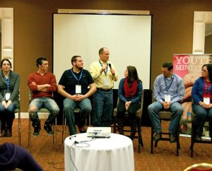 Director of Christian Education Dr. Craig Oldenburg, standing, asks a panel of six "emerging adults" at the Youth Ministry 2014 (YM14) Symposium to share their faith-formation stories by highlighting the importance of relationships and the role of their local congregations. From left, the panelists are Alex Wright, Tim Anas, Taylor Relle, Thomas Senter and Carlea Halverson. Not shown in the cropped photo is panelist Laura Davis. (LCMS Youth Ministry/Amy Gray)