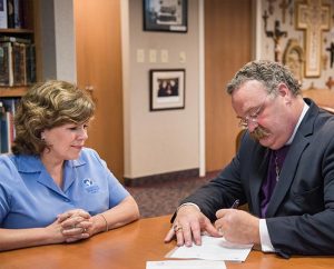 LCMS President Rev. Dr. Matthew C. Harrison signs a Memorandum of Understanding May 14, 2014, with Patti Garibay, national executive director of American Heritage Girls, at the Synod's International Center in St. Louis. (LCMS Communications/Erik M. Lunsford)