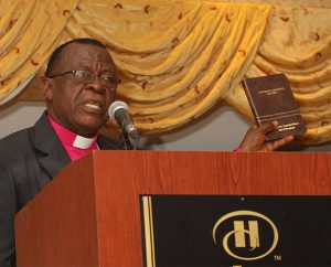 The Rt. Rev. Dr. Paul Kofi Fynn, president of the Evangelical Lutheran Church of Ghana, holds a copy of the newly published Komba New Testament as he addresses some 200-plus guests at the first Lutheran Bible Translators (LBT) 50th anniversary dinner May 2 in Lisle, Ill. The Komba translation is one of 39 completed by LBT in 18 countries. (Lutheran Bible Translators/Kellwood Studio Photography)