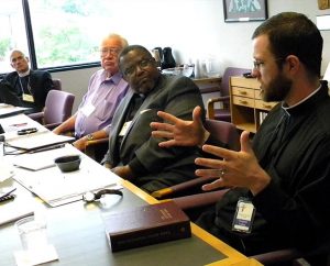 The Rev. Heath R. Curtis describes the current approach of Stewardship Ministry to the LCMS Board for National Mission (BNM) at its May 30-31 meeting. Listening to Curtis, coordinator for the Office of National Mission — Stewardship Ministry, are (from left) BNM members Rev. Steven Briel, Ernest E. Garbe and Rev. Samuel Cosby. (LCMS/Joe Isenhower Jr.)