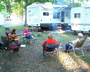 Heidi Wilkinson strums her guitar for fellow Laborers, from left, Cindy Trombley, Gary Trombley and A.J. Hunter, at the end of a day of working for Lutheran Housing Support to help Fort Wayne homeowners in need. Laborers live in their RVs, camped at a city park, during the Helping Hand project.  (Lutheran Church Extension Fund) 