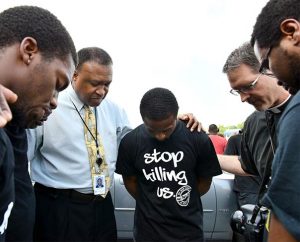 The Rev. Roosevelt Gray Jr., director of LCMS Black Ministry (second from left), and the Rev. Steven Schave, director of LCMS Urban & Inner-City Mission (second from right), pray with others along West Florissant Avenue in Ferguson, Mo., on Aug. 18. (LCMS/Erik M. Lunsford)