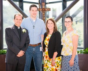 The Rev. Dan McMiller, left, poses with coworkers, from left, David Fiala, Maureen Williams and Erin Alter after his installation as director of recruitment for the LCMS Office of International Mission. (LCMS/Erik M. Lunsford)