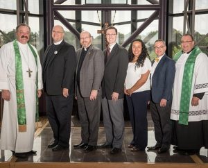 The five LCMS staff members installed Sept. 3 at the Synod’s International Center chapel stand between Synod President Rev. Dr. Matthew C. Harrison, left, and LCMS Interim Chief Mission Officer and Office of National Mission Executive Director Rev. Bart Day, right. From left, the newly installed staff members are the Rev. Marcus Zill, the Rev. Mark Wood, Matthew Bergholt, Deaconess Mireya Johnson and Ross Stroh. (LCMS/Eric M. Lunsford)