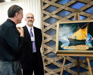 At the LCMS International Disaster Conference, artist Edward Riojas, right, shows his painting titled “Even Winds and Sea Obey Him” to LCMS Eastern District Response Coordinator Rev. Kristian Bjornstadt.  Riojas presented the painting to the pastor of St. John Lutheran Church, Pilger, Neb., whose building was torn apart by twin tornadoes earlier this year.  International representatives at the conference received a print of the artwork. (LCMS/Pamela J. Nielsen)