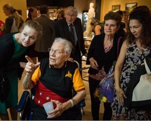 The Rev. Otto J. Hintze, commissioned as the first LCMS missionary to New Guinea (now Papua New Guinea), browses artifacts with family, including his granddaughter, Ellie Hintze (left), during the Oct. 5 public opening of Concordia Historical Institute's "Bringing Christ to the Highlands" exhibit. (LCMS/Erik M. Lunsford)