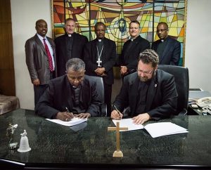 The Rev. Dr. Berhanu Ofgaa (seated, left), general secretary of the Ethiopian Evangelical Church Mekane Yesus (EECMY) and the Rev. Dr. Albert C. Collver, director of Church Relations and Regional Operations for the LCMS, sign a revised working-partnership agreement between the two church bodies Nov. 13 at the EECMY headquarters in Addis Ababa, Ethiopia. Behind them, from left, are the Rev. Dr. Tilahun Mendedo, president of Concordia College Alabama, Selma, Ala.; the Rev. Dr. Joel Lehenbauer, executive director of the LCMS Commission on Theology and Church Relations; EECMY President Rev. Dr. Wakseyoum Idosa; the Rev. Dr. Lawrence R. Rast Jr., president of Concordia Theological Seminary, Fort Wayne, Ind.; and the Rev. Yonas Yigezu, director of Mission and Theology for the EECMY. (LCMS/Erik M. Lunsford)