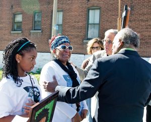 The Rev. Edward Watson (right), pastor emeritus of St. Paul Lutheran Church, and the Rev. David Vaughn (center), pastor of Christ Memorial Lutheran Church in St. Louis, offer consolation to Sandra James, a resident of College Hill whose son was killed there. (LCMS/Frank Kohn)