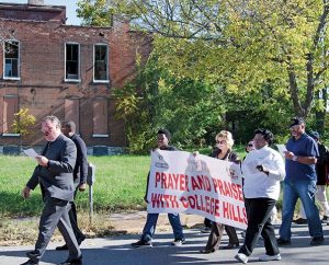 LCMS President Rev. Dr. Matthew C. Harrison and residents of College Hill pass one of the older buildings in the neighborhood during the Prayer and Praise Walk. Representatives from Lutheran Housing Support, the College Hill Foundation and the Campaign for College Hill also attended the Oct. 17 event. (LCMS/Frank Kohn)