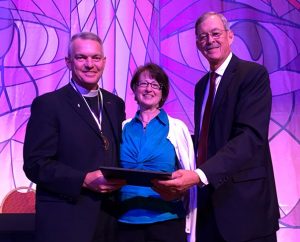 Texas District President Rev. Ken Hennings, right, presents the Bronze St. Martin of Tours Medal for 20 years of service as a military chaplain to the Rev. Dr. Mark Nuckols, chaplain, U.S. Army, Reserves (with his wife, Carla), during the district convention. Nuckols is pastor of St. Paul Lutheran Church, Austin, Texas, and Jesus Church of the Deaf in Austin. (Eloy González)