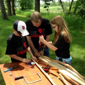 A: Norman Barge, a longtime camp volunteer, teaches "Prairie and Woods" campers at Christ Serve Ranch, Henning, Minn., how to make walking sticks. (Judy Kretzschmar)