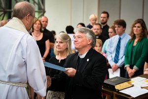 LCMS Office of International Mission Executive Director Rev. John Fale, left, presents a certificate to the Rev. Dr. Thomas Aadland at the July 2 “Service of Sending” to mark his completing two weeks of new-missionary orientation for The Lutheran Church—Missouri Synod.  Aadland will serve as an LCMS career missionary in Kenya.  With him is his wife, Mary. (LCMS/Erik M. Lunsford)