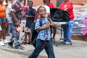 A young guest at Concordia Publishing House's Aug. 6 "Operation F.U.N." event tries on his new backpack. He was one of 850 area children who received the free backpacks filled with school supplies at CPH's 20th annual neighborhood-outreach party. (Amanda Lansche)