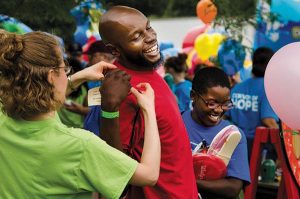 Volunteer Leah Sieveking helps a guest with his backpack. (LCMS/Frank Kohn)