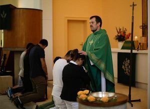 The Rev. Dr. Gottfried Martens, pastor of Trinity Lutheran Church in Berlin-Steglitz, prays with people from Iran during a Baptism service at Trinity Aug. 30. Hundreds of asylum-seekers reportedly have converted to Christianity at Trinity, a church that is part of the Selbständige Evangelisch-Lutherische Kirche (SELK), an LCMS partner church. (AP Photo/Markus Schreiber)