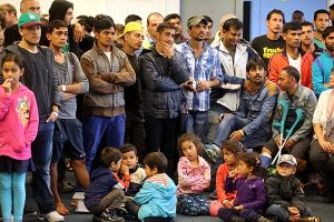 Refugees with their children watch Berlin's Governing Mayor Michael Mueller (unseen) deliver remarks during his visit to Karlshorst emergency shelter in Berlin, Germany, Sept. 14.  (AP/Wolfgang Kumm)