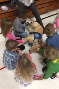 Preschoolers gather around "Lizzie," a K-9 Comfort Dog (in training) from Lutheran Church Charities, after an April 3 worship service at Martin Luther High School in Northrop, Minn. The service was the first for members of St. James Evangelical Lutheran Church, Northrop, since a March 30 fire destroyed the church building. (Lutheran Church Charities)