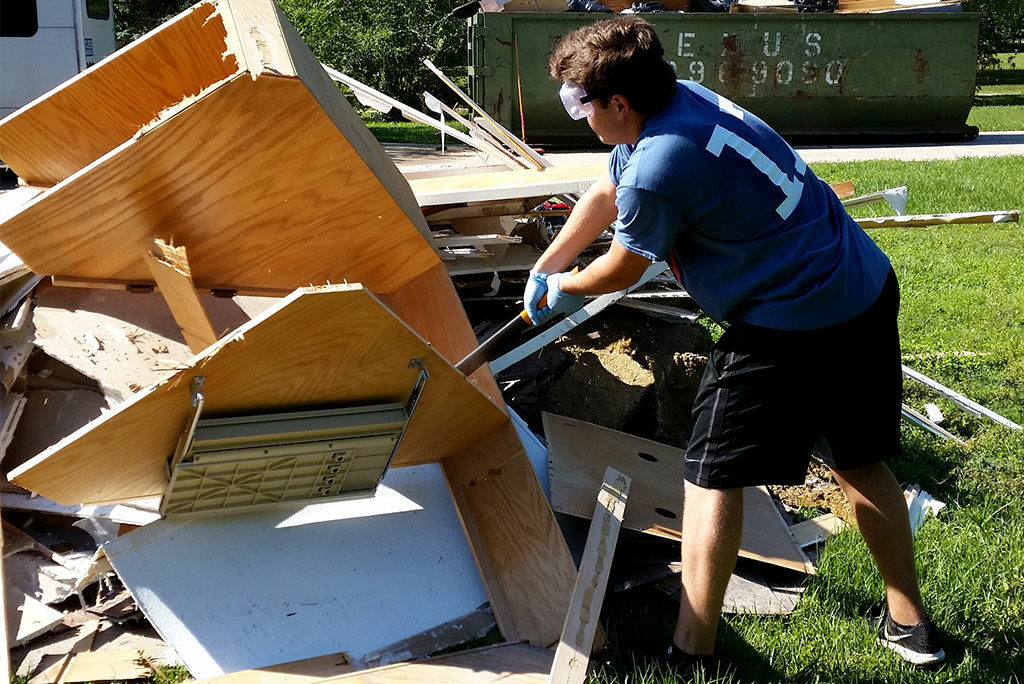 A youth member of St. Timothy Lutheran Church in Houston assists with flood cleanup in Cypress, Texas, by breaking up debris at a local Bethesda Lutheran Communities group home April 21. (Melisa May)