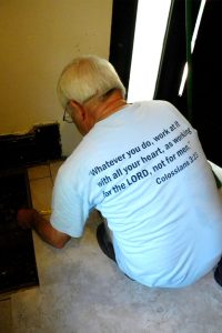 Ron Horstmann adds tile to an East St. Louis home wearing his Laborers For Christ T-shirt with a meaningful Bible verse. Horstmann calls the LCEF ministry “our way to serve the Lord.” (LCMS/Joe Isenhower Jr.)