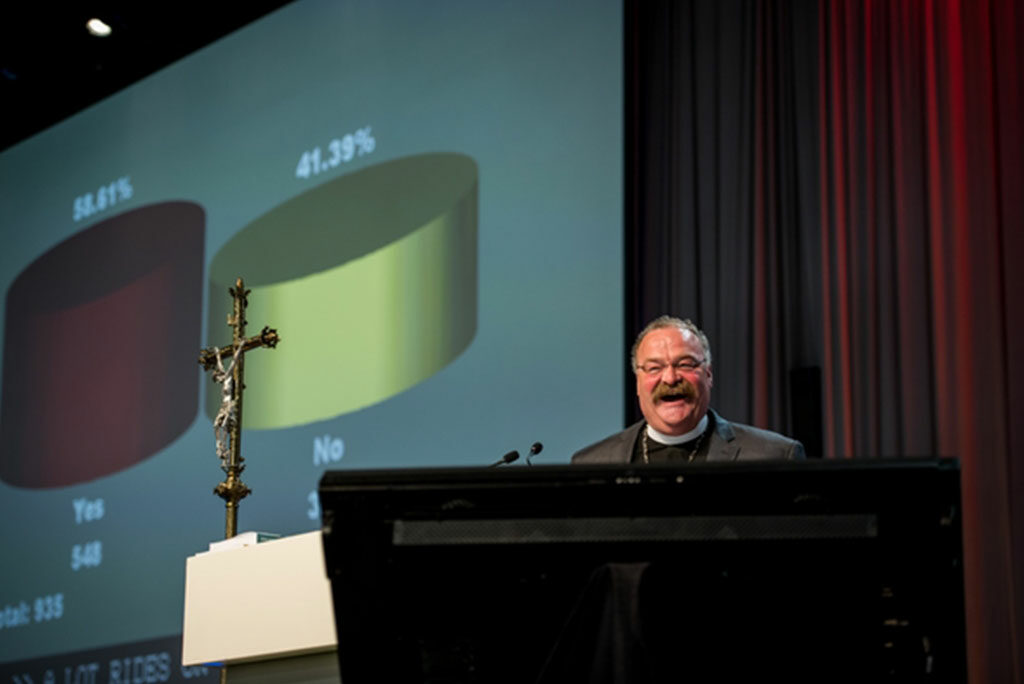 LCMS President Rev. Dr. Matthew C. Harrison reacts to the results of the July 12 balloting, projected on the screen, indicating that delegates to the 2016 Synod convention considered LCMS Montana District President Rev. Terry Forke’s mustache to be “better” than his. (LCMS/Michael Schuermann)