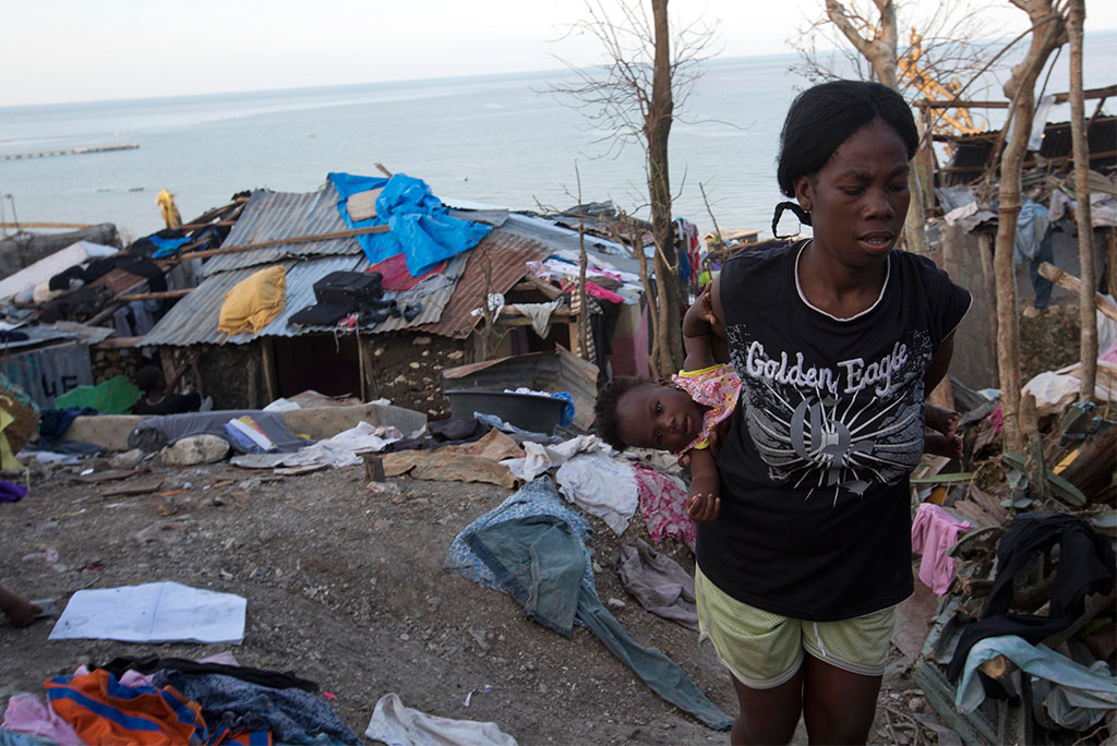 On Oct. 7, a woman carries her daughter as she walks through wreckage caused by Hurricane Matthew in Jeremie, Haiti. (AP Photo/Dieu Nalio Chery)