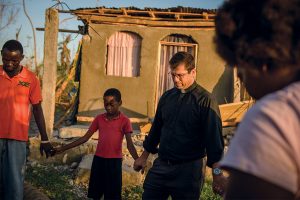 The Rev. Ross Johnson, director of LCMS Disaster Response, prays with a family outside a home severely damaged by Hurricane Matthew on Oct. 12 in a rural area of Les Cayes, Haiti. LCMS Disaster Response has provided, to date, $20,000 for 120,000 meals for people in the country's hardest-hit areas. (LCMS/Erik M. Lunsford)