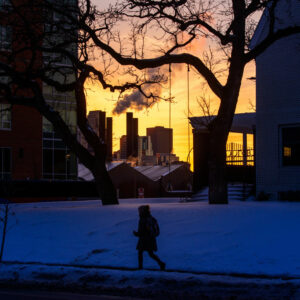 As the sun sets over the Minneapolis skyline, a pedestrian walks along 10th Avenue SE on Feb. 21, 2018, near the Luther House and the University of Minnesota. (LCMS/Erik M. Lunsford)