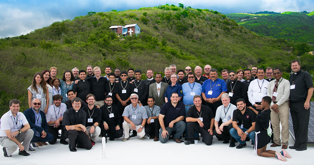 Attendees at the Heidelberg Symposium, held April 24–26 in Santiago, Dominican Republic, pose for a group photo on the white roof of the Concordia The Reformer Mercy Center and Seminary. The seminary dormitory is pictured in the background. (Jana Inglehart)