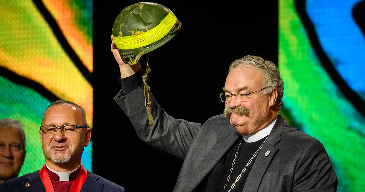 The Rev. Dr. Matthew C. Harrison, LCMS president, holds up a helmet presented to him by the Rev. Serge Maschewski, bishop of the Evangelical Lutheran Church of Ukraine. The LCMS purchased the helmet that later saved Maschewski’s life. (LCMS/Frank Kohn)