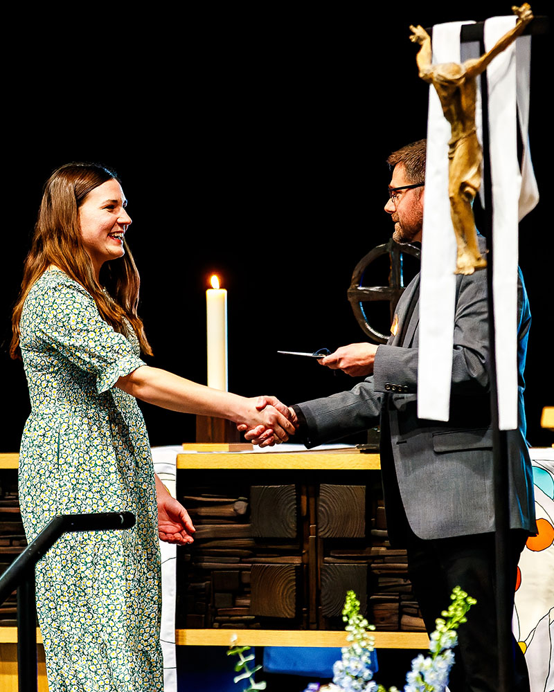 Christina Gronefeld, a 2026 graduate of Concordia University Nebraska’s DCE program, is congratulated by the Rev. Jonathan Rusnak, assistant professor of theology, during a Sending Service for church work students on May 8. (CUNE)