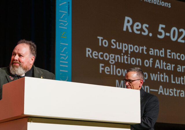 The Rev. Matthew Anker, president of Lutheran Mission–Australia, addresses The Lutheran Church—Missouri Synod convention following the passage of Res. 5-02 on July 21 while the Rev. Dr. Jonathan Shaw, director of LCMS Church Relations, looks on. (LCMS/Erik M. Lunsford)